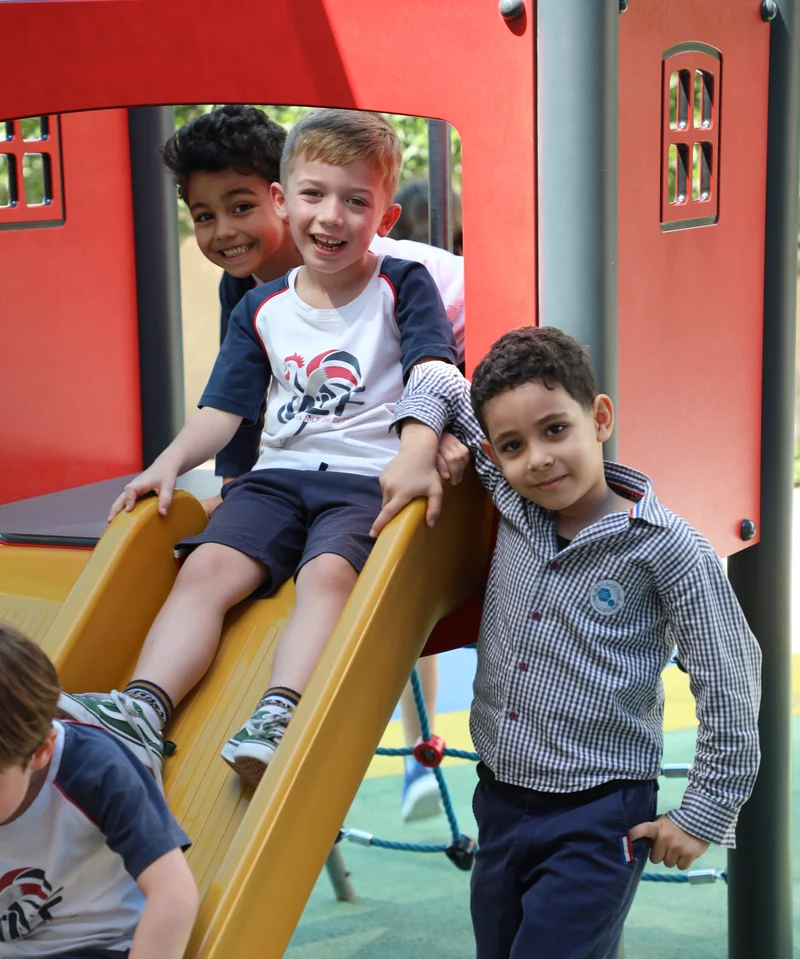 Three LFIB students enjoying the playground slide
